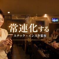 スナック店内でスマートフォンを操作する日本人女性オーナーと、常連客が会話を楽しむ様子