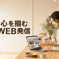 自然光が入る実店舗で、パソコンとスマートフォンを使ってWEB発信を行う日本人女性店主と「心を掴むWEB発信」の文字を配置した画像